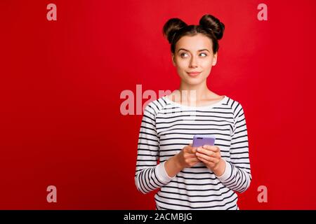 Portrait von gleichgesinnten Mädchen Smartphone verwenden denken Gedanken entscheiden, was Post am sozialen Netzwerk suchen Kopieren Raum tragen gestreifte Pullover weiß über Rot isoliert Stockfoto