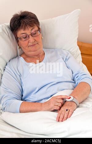 Senioren mit Ruf Hile Notruf im Bett Stockfoto