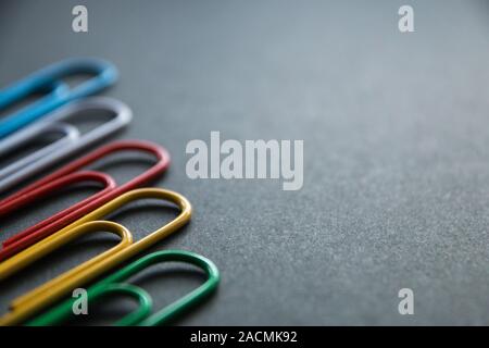 Bunte Büroklammern auf dunklem Hintergrund, Schreibwaren. Stockfoto