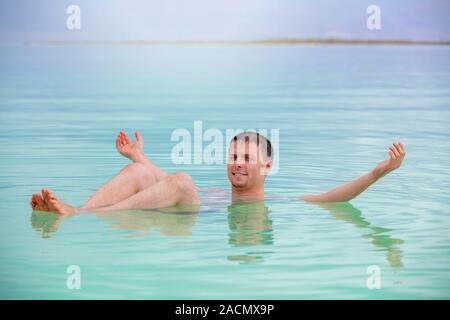 Mann mit den Händen in der Luft schwimmen im Toten Meer. Spa verfahren. Sommer, Urlaub, Reise-Konzept. Szene aus dem Toten Meer Stockfoto