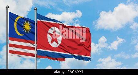 Malaysia und Nordkorea Fahne im Wind gegen Weiße bewölkt blauer Himmel zusammen. Diplomatie Konzept, internationale Beziehungen. Stockfoto