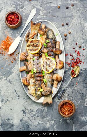 Ganze pelengas Fisch mit Pilzen und Zitrone gebacken. Sea Food. gegrillter Fisch mit Pilzen. Stockfoto
