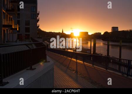 Sonnenaufgang an der Weser in Bremen mit modernen Wohngebäuden im Vordergrund und dem Bau eines Bürogebäudes im Hintergrund Stockfoto