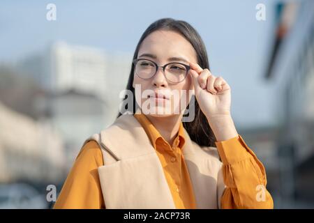 Jungen asiatischen hübsche Frau ihre Brille Holding Stockfoto