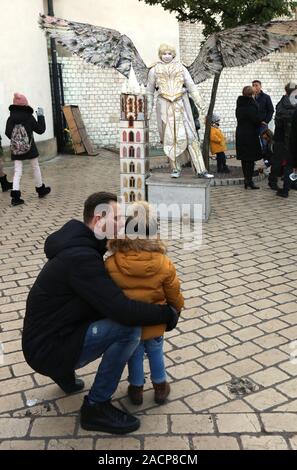 Krakau. Krakau. Polen. Weihnachten jährliche Straßenfest auf dem Marktplatz. Vater mit Kind vor Straße Schauspieler in Engel Kostüm. Stockfoto