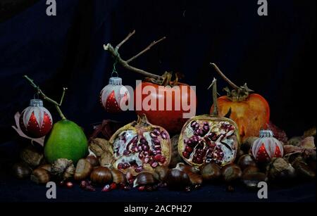 Herbst Früchte mit roten Christbaumkugeln auf schwarzem Hintergrund Stockfoto