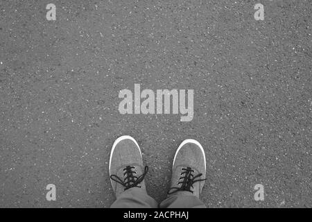 Füße in Canvas Schuhe stehen auf Straße - Fuß selfie aus persönlicher Perspektive betrachtet - Asphalt Hintergrund mit Kopie Raum Stockfoto