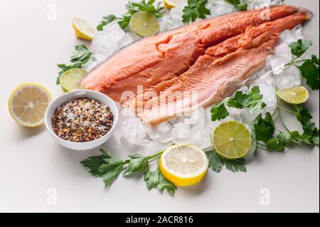 Close-up frischen appetitlichen Lachssteak. Gewürze, Zitrone, frische Petersilie und Eis. Hellen Hintergrund. Ökologische Lebensmittel Stockfoto