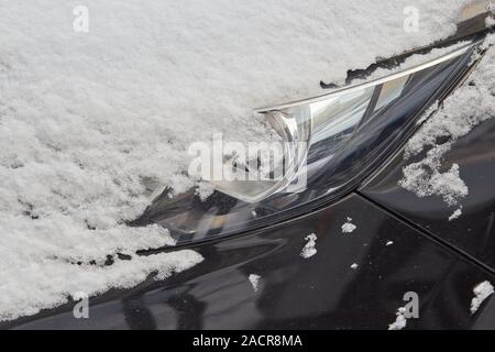 Scheinwerfer der schwarzen Farbe Auto im Winter mit Schnee closeup abgedeckt Stockfoto