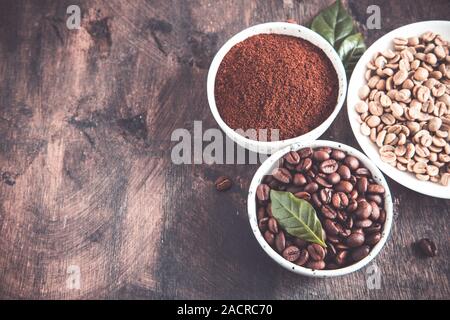 Kaffeebohnen und gemahlenen Kaffee in Schalen mit Kaffee Baum Blatt auf einem dunklen Hintergrund.. Kopieren Sie Platz für Ihren Text Stockfoto