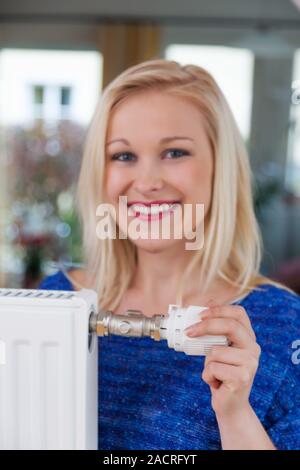 Frau senkt die Raumtemperatur Stockfoto