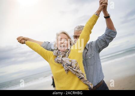 Lebhafte senior Paar rund um das Spielen am Strand zusammen Stockfoto