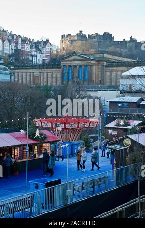 Das Edinburgh Castle, Weihnachtsmarkt und Fair. Karussell und Markt im Vordergrund. Schottland Stockfoto