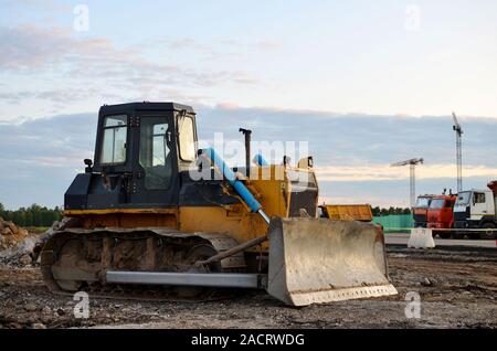 Anschluss - Typ Bulldozer auf der Baustelle. Flurbereinigung, Sortierung, Pool, Aushub, Grabenaushub und Fundament graben während der Großen konstruieren Stockfoto