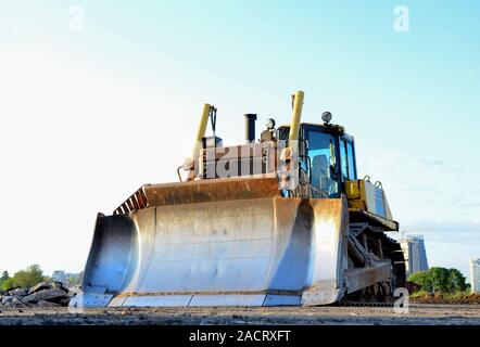 Anschluss - Typ Bulldozer auf der Baustelle. Flurbereinigung, Sortierung, Pool, Aushub, Grabenaushub und Fundament graben während der Großen konstruieren Stockfoto