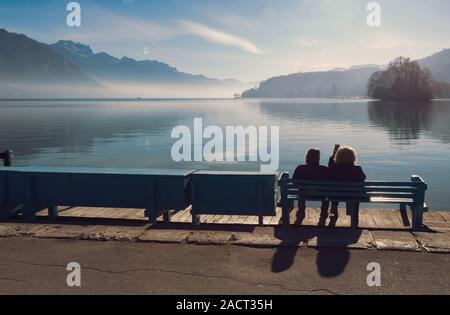 Ansicht von hinten Paar Silhouette in der vor dem See von Annecy in Frankreich im Winter an einem sonnigen Tag Stockfoto
