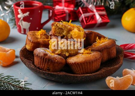 Hausgemachte Muffins mit Mandarinen, bestreut mit Puderzucker auf der Silvester oder Weihnachten hellblauen Hintergrund entfernt Stockfoto