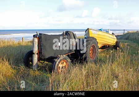 Ein Traktor und kleinen Boot für den Winter weg den Strand in Bacton, Norfolk, England, Vereinigtes Königreich, Europa gelegt. Stockfoto