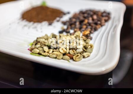 Grüne ungerösteten äthiopischen Kaffee Bohnen, mit gerösteten und gemahlenen Kaffeebohnen im Hintergrund Stockfoto