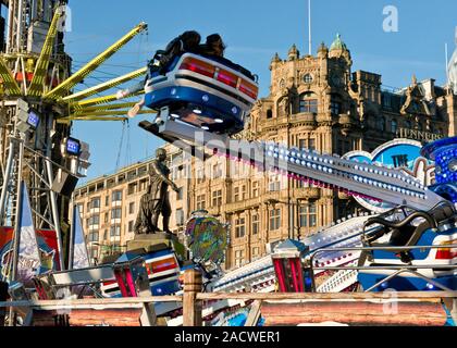 Yeti und Star Flyer Fahrgeschäfte. Edinburgh Weihnachtsmarkt und Fair. Jenners Kaufhaus auf der Princess Street im Hintergrund. Schottland Stockfoto