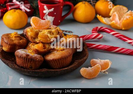 Hausgemachte Muffins mit Mandarinen, bestreut mit Puderzucker auf der Silvester oder Weihnachten hellblauen Hintergrund entfernt Stockfoto