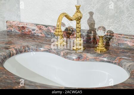 Waschbecken aus teuren Marmor Stein. Vintage Design von Hahn und Armaturen, in Gold und Glas verarbeitet. Glasmalerei teuer Bad design Stockfoto