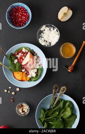 Eine Schüssel mit gesunden Lebensmitteln. Früchte mit Spinat und Frischkäse sind gewürzt mit Honig und Nüssen. Ökologische Lebensmittel. Stockfoto