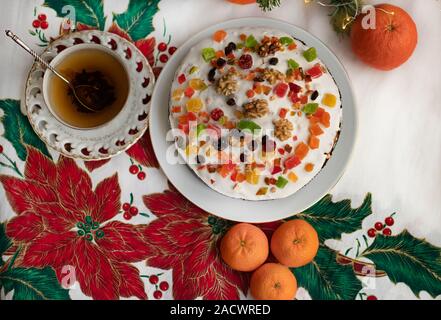 Christstollen, Panettone, Brioche, Kuchen mit weißer Zuckerglasur, Marzipan, Rosinen, getrocknete Früchte, eine Tasse Tee und Orangen Mandarinen auf dem fest Stockfoto