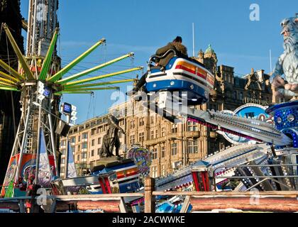 Yeti und Star Flyer Fahrgeschäfte. Edinburgh Weihnachtsmarkt und Fair. Jenners Kaufhaus auf der Princess Street im Hintergrund. Schottland Stockfoto