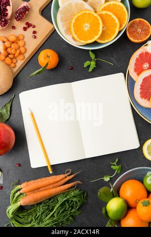 Lebensmittel, gesunde Ernährung und Diät Konzept - aus der Nähe von Notebook, Früchte und Gemüse auf schiefer Table Top Stockfoto