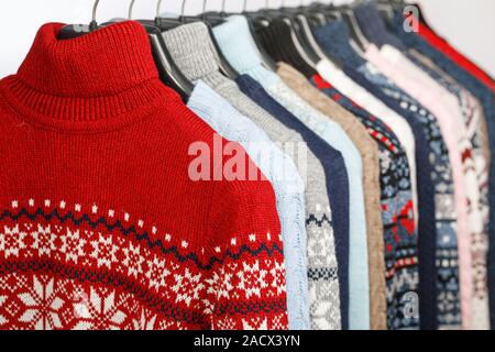 Verschiedene gestrickt Rollkragen Strickjacken und Pullover mit norwegischen Ornament auf Bügel in einem Bekleidungsgeschäft oder an einem Schrank, selektiven Fokus Stockfoto