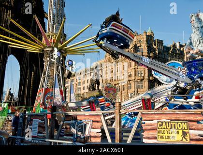 Yeti und Star Flyer Fahrgeschäfte. Edinburgh Weihnachtsmarkt und Fair. Jenners Kaufhaus auf der Princess Street im Hintergrund. Schottland Stockfoto