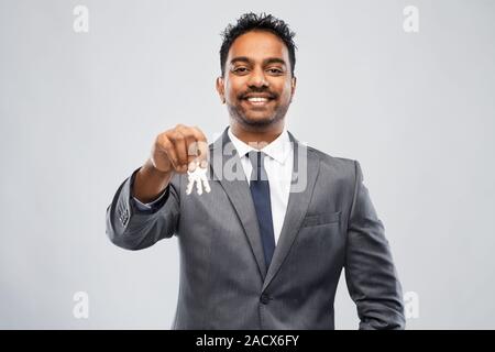Immobilien Unternehmen und Personen Konzept - Inder Realtor mit Schlüssel über grauer Hintergrund Stockfoto