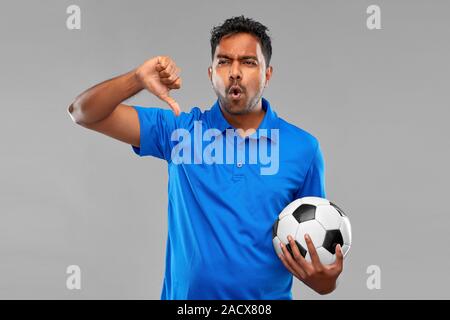 Sport, Freizeit Spiele und Ausfall Konzept - enttäuscht, Inder oder Fußball-Fan mit Fußball, Daumen nach unten Geste über grauer Hintergrund Stockfoto