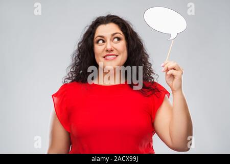 Partei Requisiten, Photo Booth und Kommunikationskonzept - glückliche Frau im roten Kleid, die große leere Sprechblase über grauer Hintergrund Stockfoto
