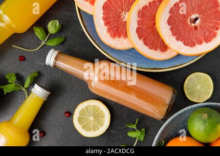 Lebensmittel, gesunde Ernährung und vegetarische Konzept - Glasflaschen mit Frucht- und Gemüsesäften auf schiefer Table Top Stockfoto