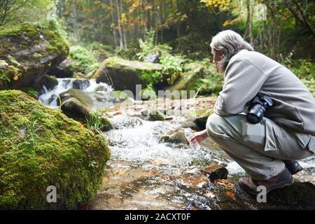 frisches Trinkwasser vom Frühling Mann Stockfoto