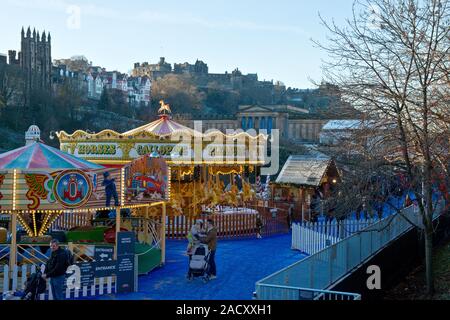 Das Edinburgh Castle, Weihnachtsmarkt und Fair. Karussell und Markt im Vordergrund. Schottland Stockfoto