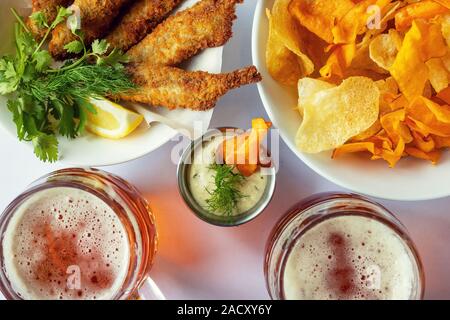 Krug mit Bier Bier und Snacks. Gebratener Fisch mit Pommes und Sauce. Stockfoto