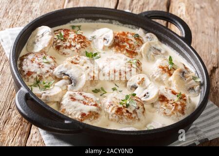 Hausgemachte Frikadellen mit Champignons in eine cremige Soße mit Thymian closeup in einer Pfanne auf dem Tisch gekocht. Horizontale Stockfoto