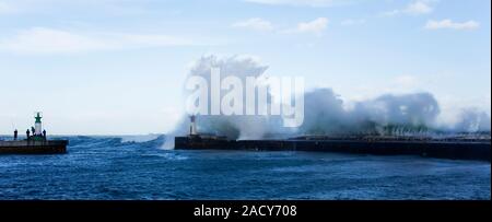 Wellen, die über Leuchtturm im Hafen von Kalk Bay als Fischer Sturm trotzen, Kapstadt, Südafrika. Stockfoto