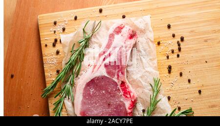 Rohe Fleischstücke mit Rosmarin und Gewürzen Stockfoto
