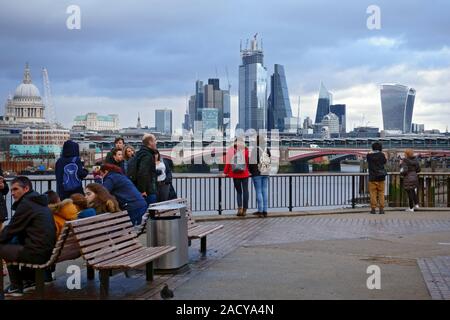 Die Leute an der Skyline von London und seinen ikonischen Gebäude am Nordufer der Themse von der South Bank suchen. Stockfoto