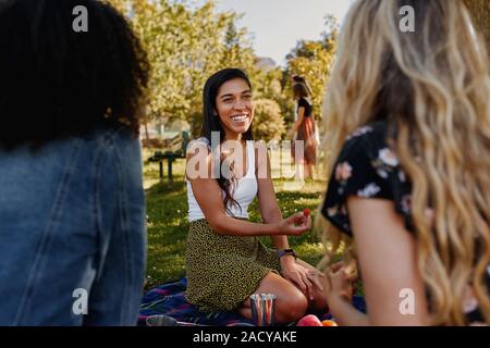Portrait eines glücklichen jungen weiblichen Freunde sitzen auf grünen Rasen der Zeit zusammen verbringen in park-Gruppe von weiblichen Freunde bei einem Picknick in der Stockfoto