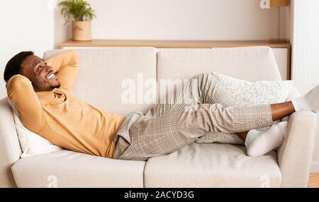 Sorglos African American Guy liegt entspannt auf einem Sofa zu Hause Stockfoto