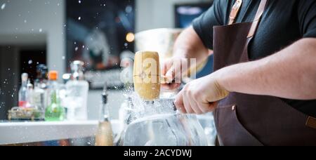 Barkeeper bricht Eis mit Holzhammer Stockfoto