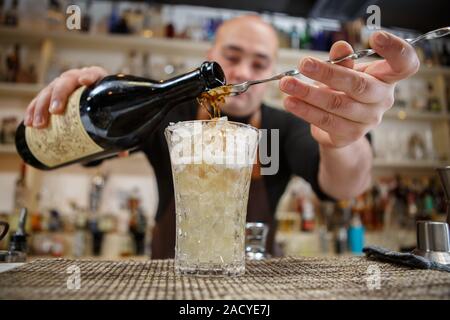 Barkeeper in Glas an der Bar cocktail gießen Stockfoto