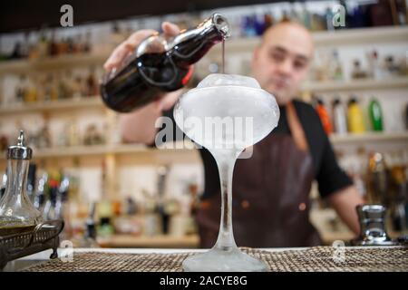 Barkeeper gießt Wein im Glas mit Rieseneishöhle, Weitwinkel-Bild. Stockfoto