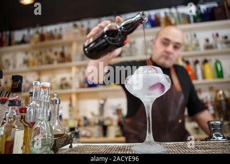 Barkeeper gießt Wein im Glas mit Rieseneishöhle, Weitwinkel-Bild. Stockfoto