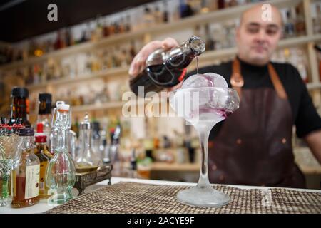 Barkeeper gießt Wein im Glas mit Rieseneishöhle, Weitwinkel-Bild. Stockfoto